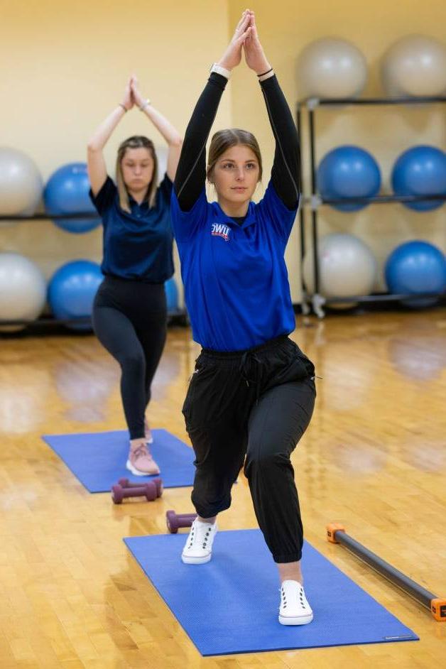 在线博彩 students in a yoga class holding a yoga pose